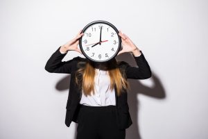 Beautiful business woman holding in hands clock isolated on white background