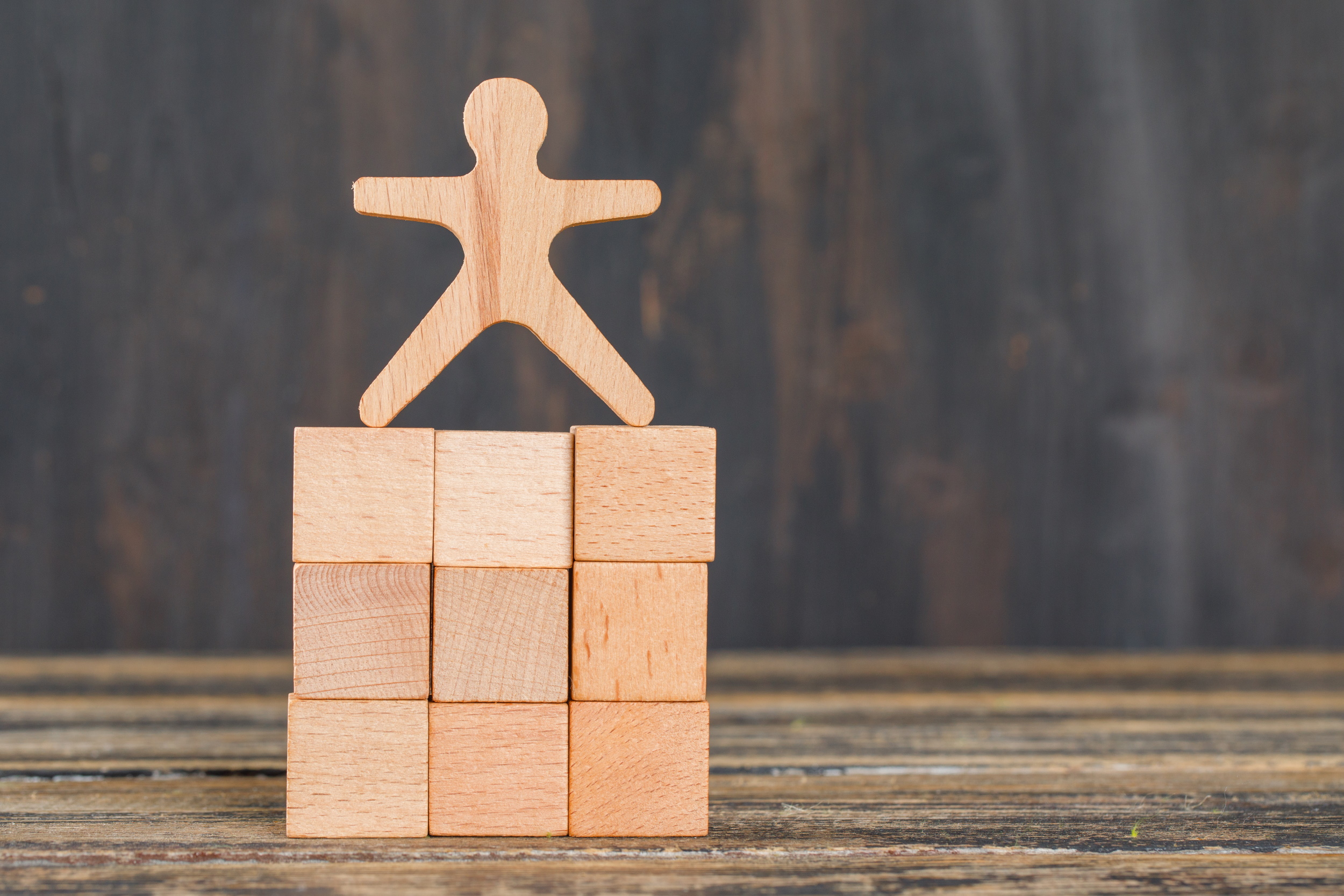 business-success-concept-with-human-model-on-wooden-cubes-on-wooden-table-side-view