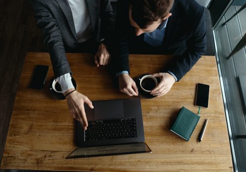 Two businessmen pointing laptop screen while discussing Two handsome businessmen