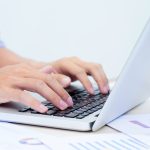 Man's hands typing on laptop keyboard